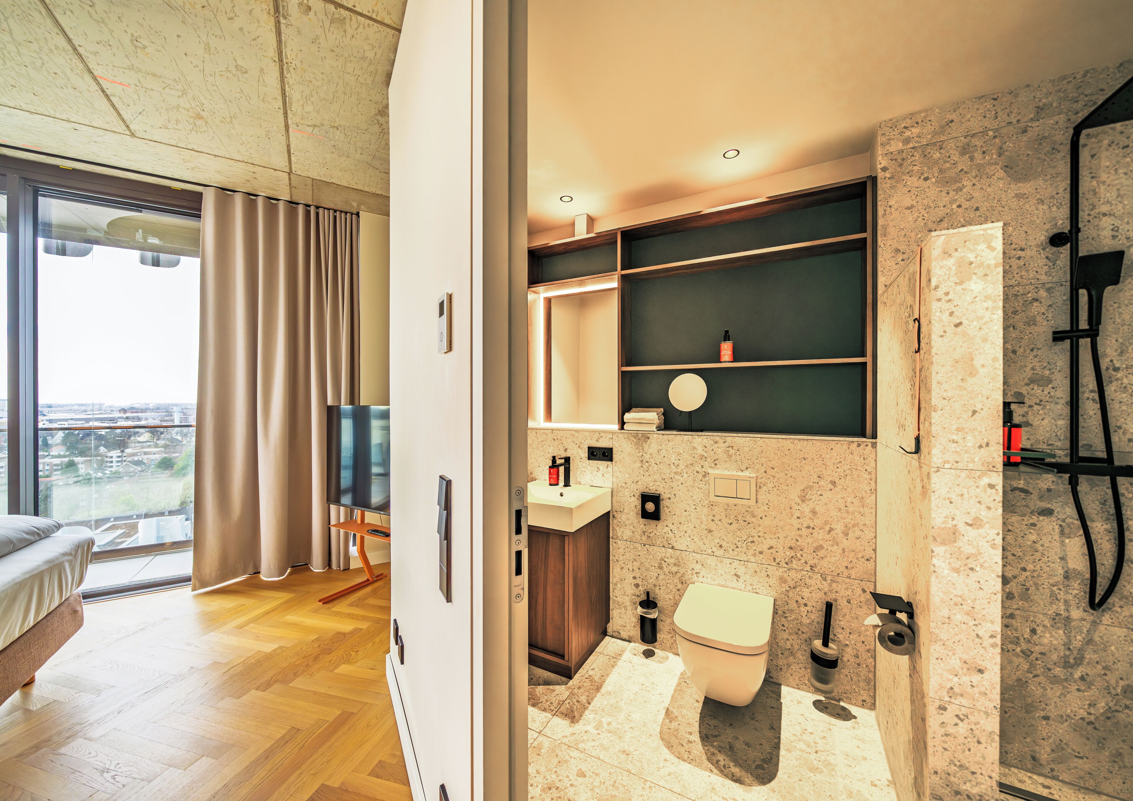 Une salle de bain moderne comprenant des toilettes, un lavabo et un miroir, ainsi que des étagères en bois et un espace douche.