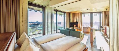A hotel room with a large bed, a TV, a desk, and a view of the city.