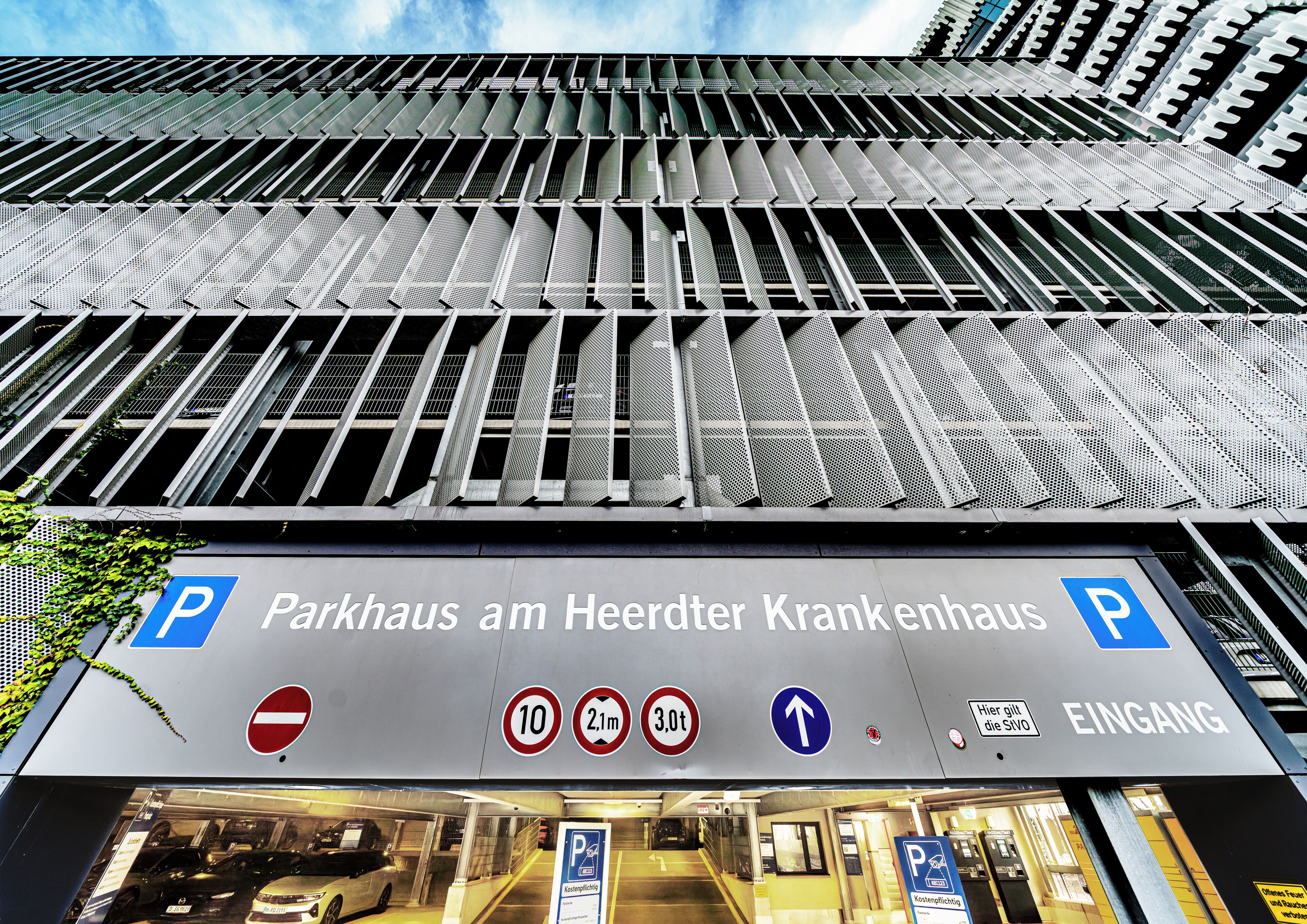 A parking garage entrance with signage for 'Parkhaus am Heerdert Krankenhaus' and directional arrows.