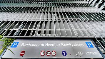 A parking garage entrance with signage for 'Parkhaus am Heerdert Krankenhaus' and directional arrows.