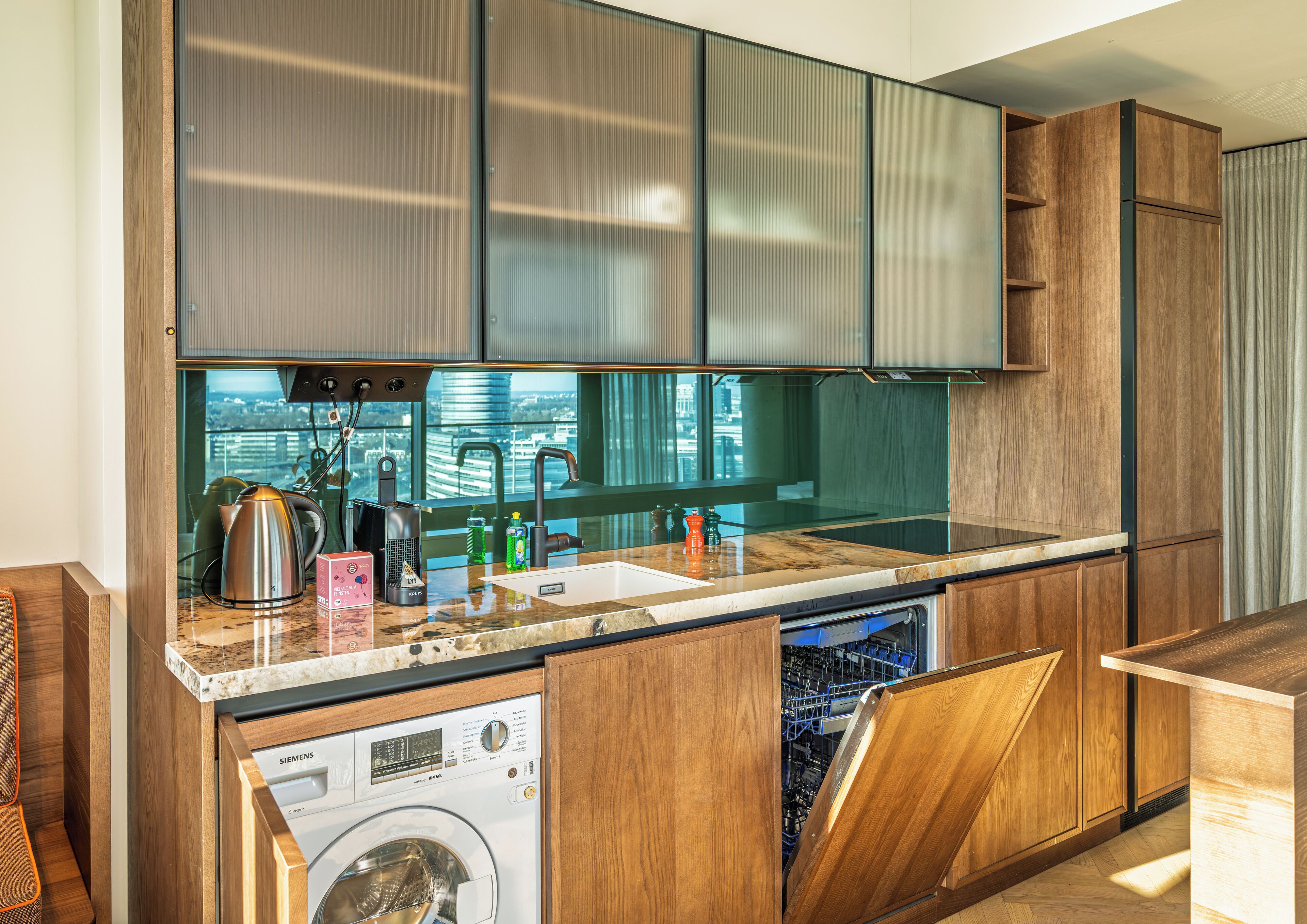 Una cucina moderna con lavastoviglie integrata, bollitore in acciaio inossidabile e vista sulla città.