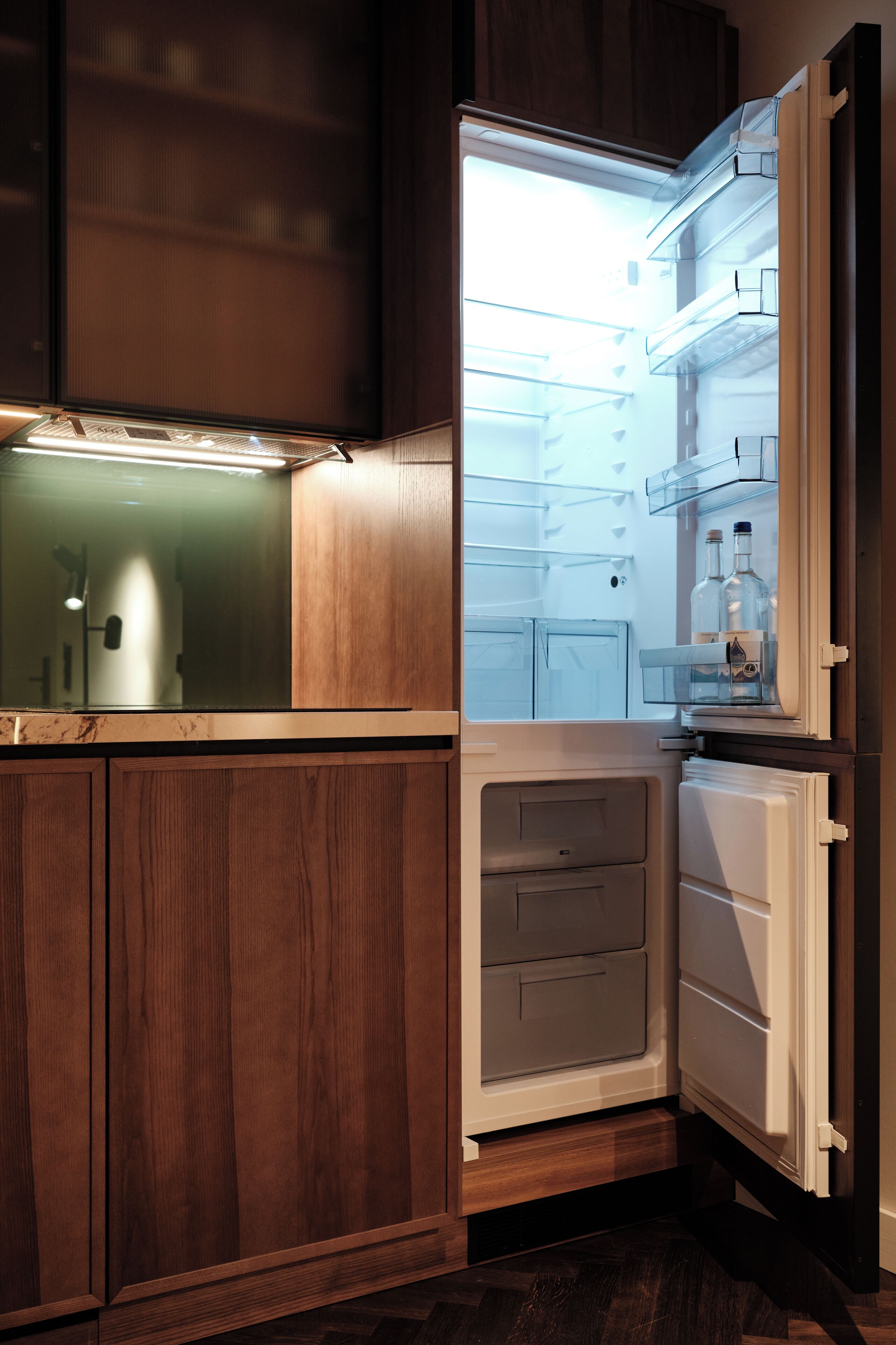 A modern kitchen with wooden cabinets, a built-in refrigerator, and a microwave.