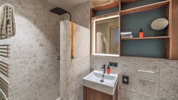 Une salle de bain moderne équipée d’une douche, d’un lavabo et d’un miroir.