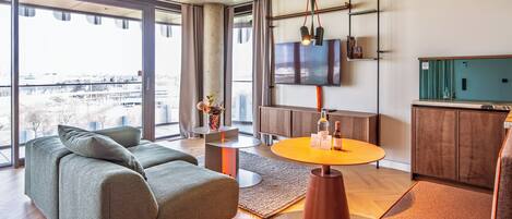 A modern living room with a sofa, a round table, and a TV mounted on the wall.