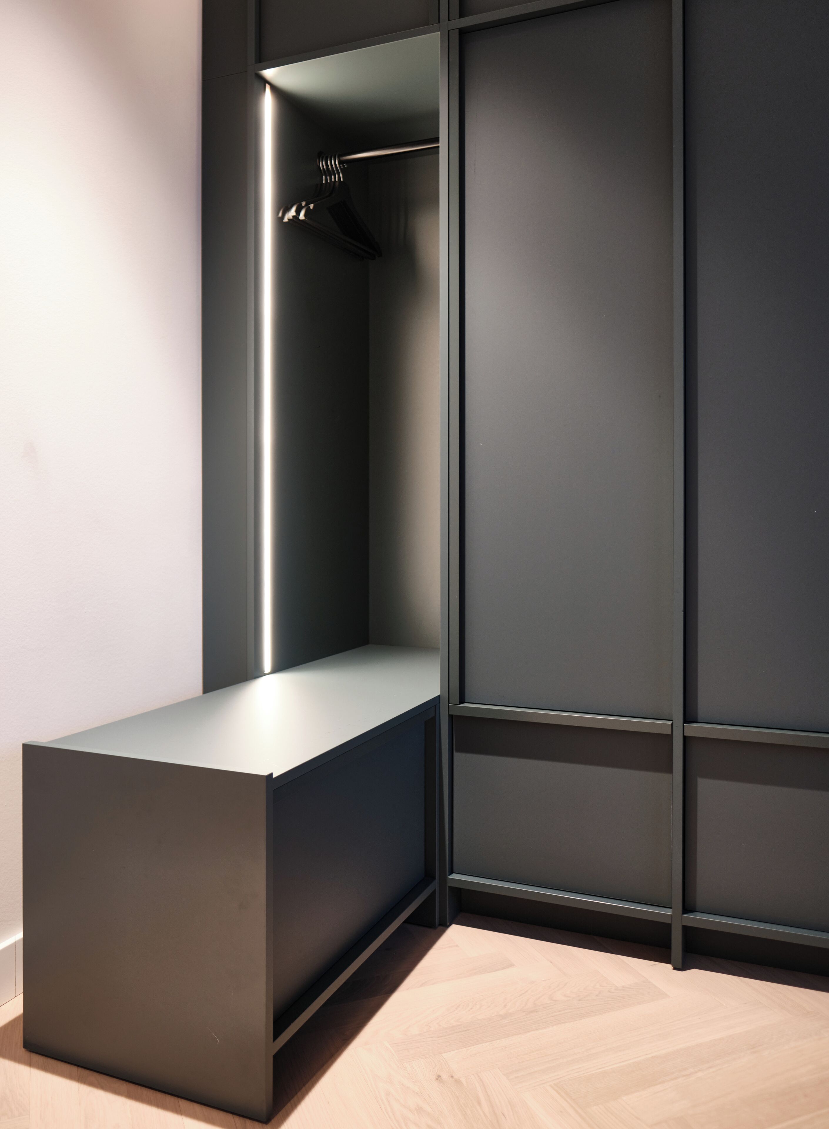 Una habitación moderna y minimalista con un banco empotrado y un armario con puertas correderas.