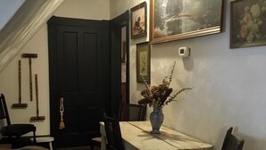 Una habitación con una mesa de comedor, sillas, un florero con flores y un cuadro en la pared.