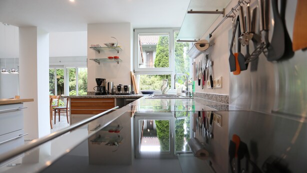 Una cocina moderna con una isla central, electrodomésticos de acero inoxidable y vistas al exterior a través de amplios ventanales.
