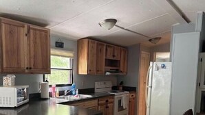 A compact kitchen with wooden cabinets, a central island, a refrigerator, and a microwave. - Tranquil Quietness (Huntingdon)
