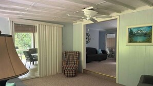 A living room with a ceiling fan, a plaid armchair, a sofa, and a painting on the wall. - Tranquil Quietness (Huntingdon)