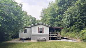 A small, single-story cabin with a picnic table and a covered porch, surrounded by dense forest. - Tranquil Quietness (Huntingdon)