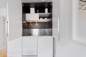 Una cocina compacta con horno integrado, un lavamanos y un microondas.