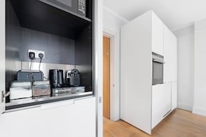 Una cocina compacta con horno integrado y cafetera.