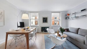 Uma sala de estar moderna com área de jantar, sofá, mesa de centro e lareira.