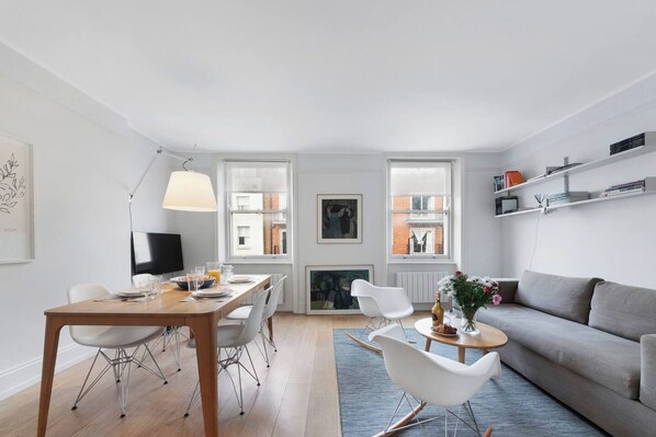 A modern living room with a dining area, a sofa, a coffee table, and a fireplace.