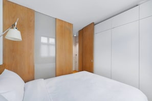 Un dormitorio moderno con cama, armario de madera y una lámpara de noche.
