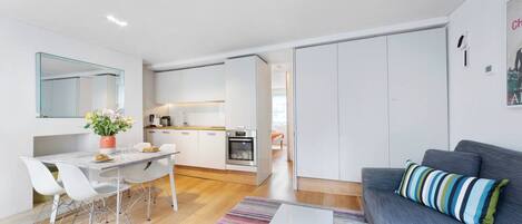 Un apartamento moderno con comedor, cocina y sala de estar con sofá y alfombra a rayas.