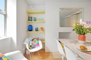 Una cocina moderna con armarios blancos, encimera de madera y un comedor con sillas blancas.