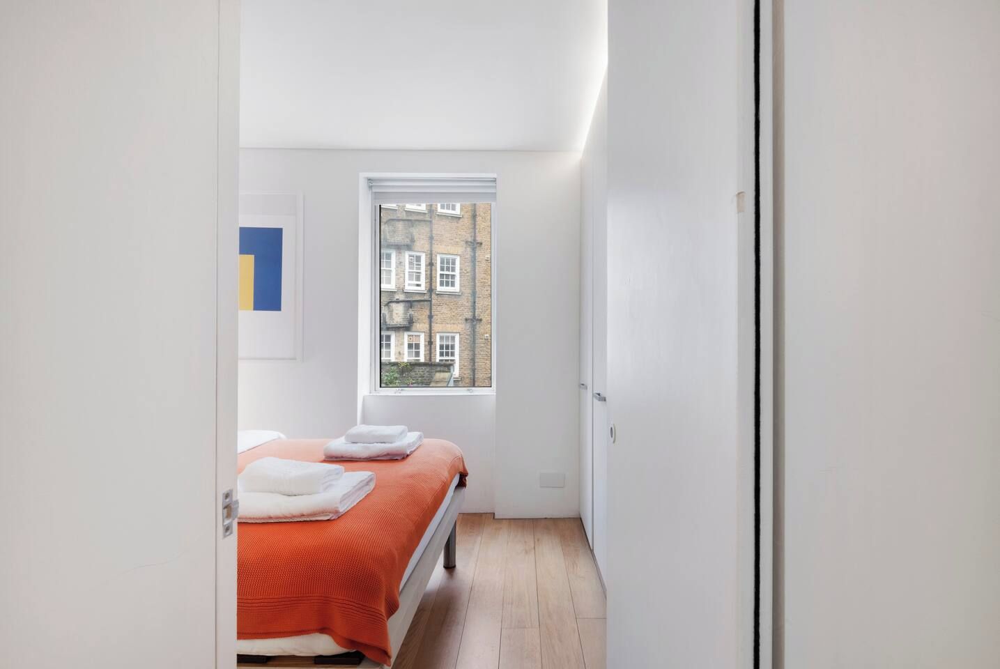 A bedroom with a bed, a window, and a door.