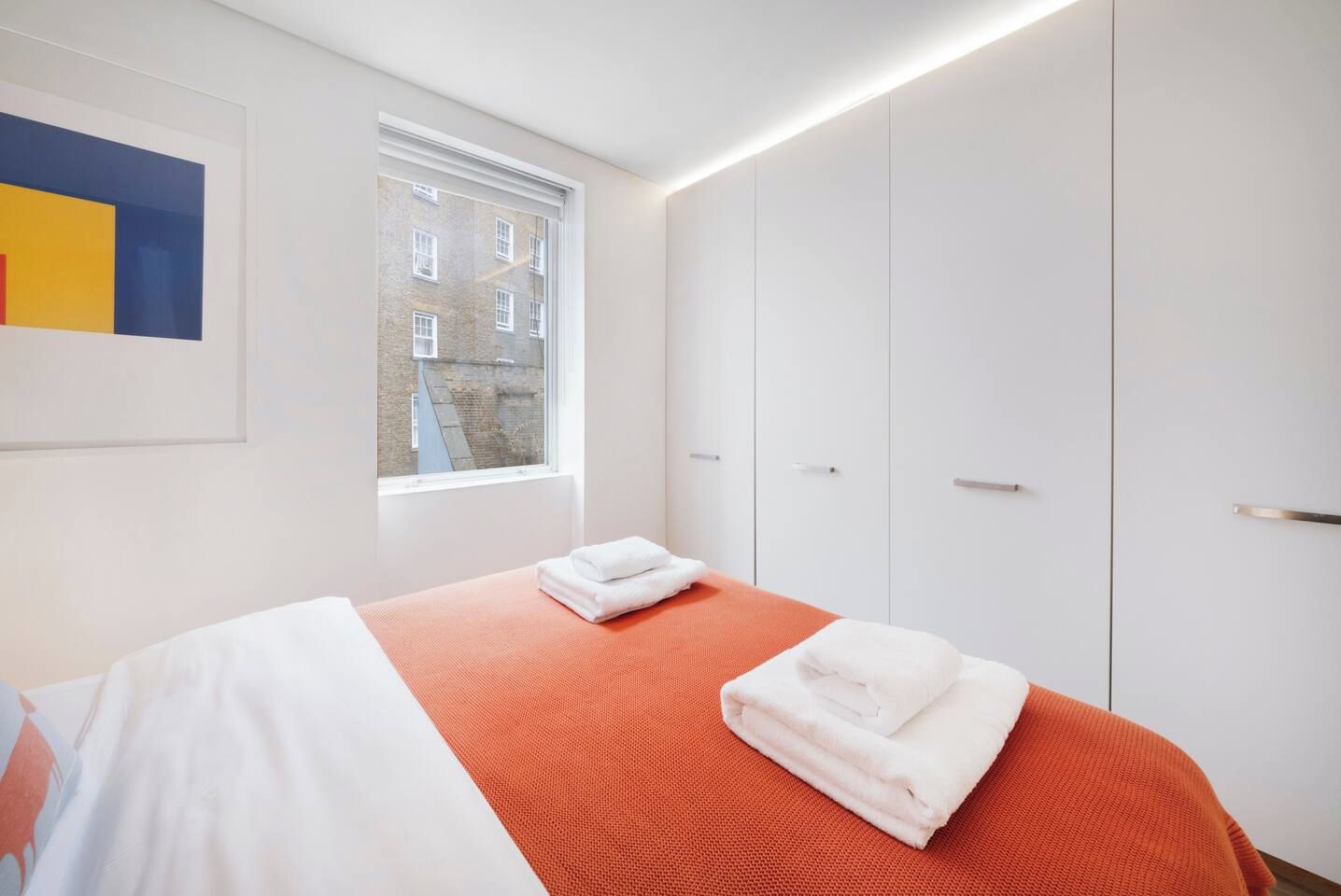 Een hotelkamer met een bed, een raam en een kledingkast.
