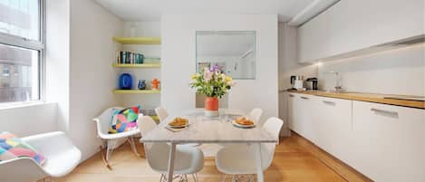 Una cocina moderna con armarios blancos, una mesa de comedor con sillas y una ventana con vistas.