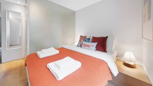 Ein modernes Hotelzimmer mit einem Bett, einem Nachttisch und einer Wandleuchte.