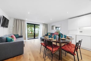 A modern living room with a grey sofa, a dining table with chairs, and a kitchen area with cabinets. - Hermitage Rd N4, Manor House | GroundFl | Garden (Greater London)
