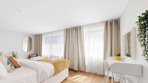 A modern hotel room with a bed, a desk, and a large window with curtains. - Hermitage Rd N4, Manor House | GroundFl | Garden (Greater London)