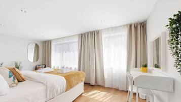 Ein modernes Hotelzimmer mit einem Bett, einem Schreibtisch und einem großen Fenster mit Vorhängen.