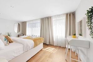 A modern hotel room with a bed, a desk, and a large window with curtains.