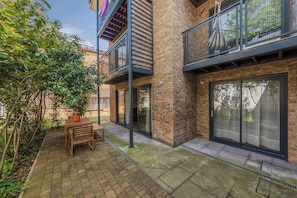 A modern building with a brick facade, a wooden table and chairs, and a covered outdoor area.