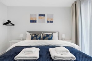 A hotel room with a bed, two pillows, a hanging black hanger, and three wall art pieces. - Hermitage Rd N4, Manor House | GroundFl | Garden (Greater London)