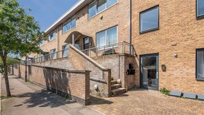 A multi-story brick building with a staircase leading to a balcony, a fire hydrant, and a mailbox. - Hermitage Rd N4, Manor House | GroundFl | Garden (Greater London)