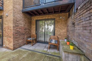 A brick exterior with a glass door entrance, two wooden chairs, and potted plants. - Hermitage Rd N4, Manor House | GroundFl | Garden (Greater London)