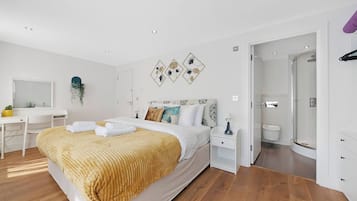 Ein modernes Schlafzimmer mit Bett, Nachttischen, einem Schreibtisch und einer Duschkabine.