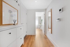 Un pasillo con un armario blanco, un cuadro enmarcado y un espejo en la pared.