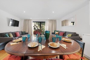 A dining area with a round table, two sofas, and a TV mounted on the wall. - Hermitage Rd N4, Manor House | GroundFl | Garden (Greater London)