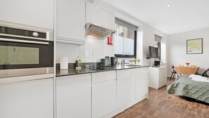 Eine moderne Küche mit weißen Schränken, einem eingebauten Backofen und einem Essbereich mit Holztisch und -stühlen.