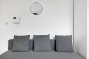 Simple, serene space with a single bed and a round mirror above.