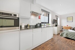Une cuisine moderne avec des meubles blancs, un four encastré et un coin repas comprenant une table et des chaises.