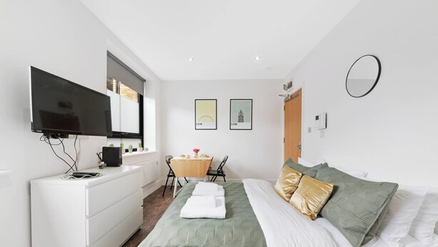 Une chambre d’hôtel moderne équipée d’un lit, d’un bureau, d’une télévision et d’une fenêtre.