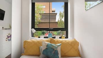 A bedroom with a bed, a window, and a view of a building outside.