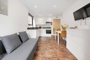 Un espacio habitable compacto con sofá, mesa de comedor y kitchenette.