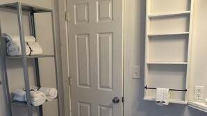 A bathroom with a white door, a metal towel rack, a white sink, and a mirror cabinet.
