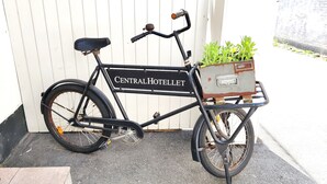 Een fiets met een bordje waarop 'CentralHotellet' staat en een mand met planten.