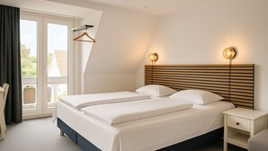 Een slaapkamer met een groot bed, twee nachtkastjes, een houten hoofdbord en uitzicht door een schuifdeur.