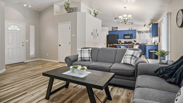 A modern living room with a sectional sofa, a coffee table with a plant, and a kitchen in the background.