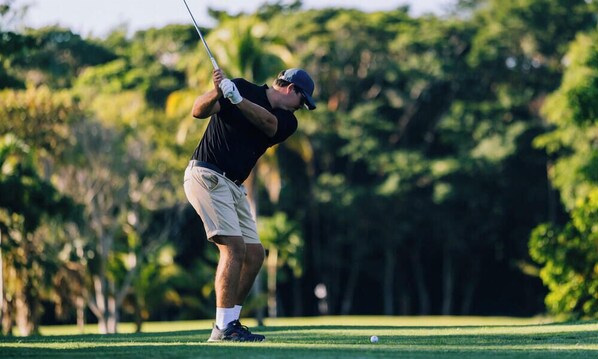 A person playing golf on a course with trees in the background. - TBS 33A Beachside Resort Condo-Pool-Studio unit (Placencia)