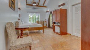 A bedroom with a bed, a small table, a chair, a wardrobe, and a ceiling fan. - TBS 35A Studio-Garden View-Shared Pool-Beachfront (Placencia)