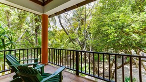 A balcony with green chairs and a view of dense tropical foliage. - TBS 35A Studio-Garden View-Shared Pool-Beachfront (Placencia)