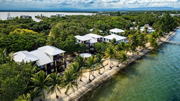 Ein Küstenort mit mehreren bungalowartigen Gebäuden, einem Sandstrand und freiem Blick auf den Ozean.